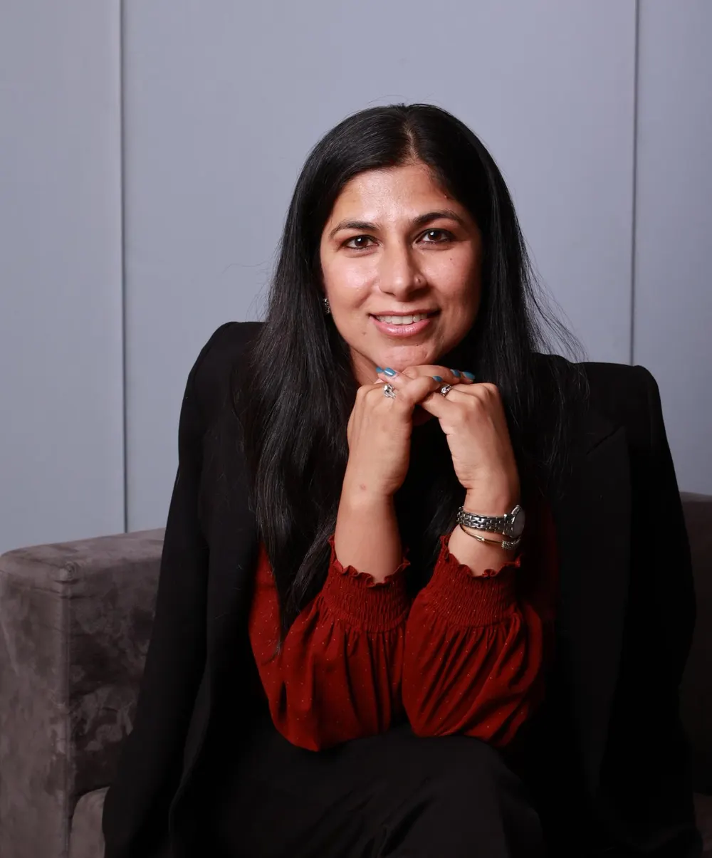 Priya Mann, smiling, chin resting on her hands